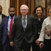 Mitch McConnell, entouré de plusieurs personnes, quitte l'hémicycle du Sénat.