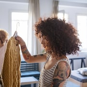Une femme tient un pull sur un cintre. 
