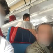 Les deux hommes, aux visages floutés, sont assis dans l'avion.