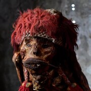 Photo d'une momie coiffée d'un accessoire rouge. 