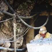 Un ouvrier avec un casque près de la sortie d'une mine.