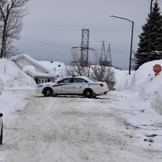 Une voiture de police est stationnée en travers d’une rue dans un quartier résidentiel de Val-Bélair.