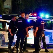 Des policiers sont regroupés aux abords d'une scène de crime potentielle.