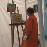Une femme en train de peindre un tableau représentant un éléphant.