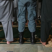 Trois personnes dans une mosquée, de dos.