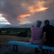 Un couple regarde le feu de forêt Mount Law, près de Peachland et Glenrosa, du côté de l'ouest du lac Okanagan, le 15 août. 