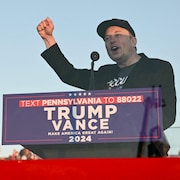 Elon Musk parle en levant le poing, tandis que Donald Trump sourit à ses côtés.