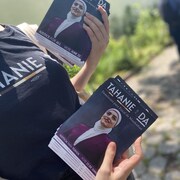 Une femme tient deux piles de dépliants de campagne de Tahanie Aboushi.