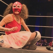 Une lutteuse masquée assise dans le ring.