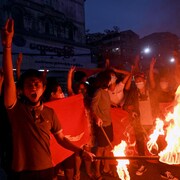 Des manifestants brûlent des drapeaux.