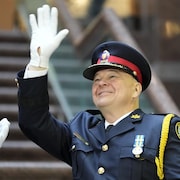 Myron Demkiw  en uniforme de chef de la police salue la foule lors d'une cérémonie.