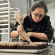 Nadège Nourian décore des gâteaux à l'aide d'une poche à douille, dans son laboratoire de pâtisserie à Etobicoke. 