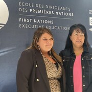 Deux femmes devant une affiche de l'École des dirigeants des Premières Nations.