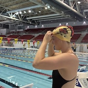 Une nageuse est &agrave; l'ext&eacute;rieur de la piscine et met ses lunettes.