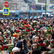 Des milliers de personnes avec des fleurs, un train dernière. 