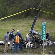 Des enquêteurs près d'un avion amoché.