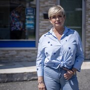 Une femme vêtue en bleu pose devant un immeuble.