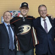 Nathan Gaucher portant le chandail des Ducks d'Anaheim, entouré de membres de la direction de l'équipe.  