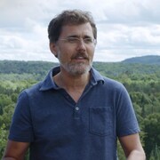 Un homme se tient debout devant une forêt.