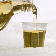 Un liquide jaune pâle versé dans un petit verre déposé sur de la neige.