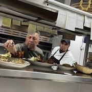 Le chef Javier Barajas saupoudre quelques &eacute;pices sur les plats qu'il pr&eacute;pare dans la cuisine de l'un de ses restaurants; un de ses cuistots observe son geste.