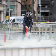 Un policier utilise un extincteur dans un espace clôturé vide à New York.