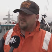 Un pêcheur devant son bateau, en entrevue.