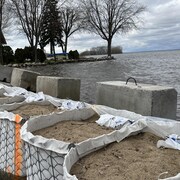 Des sacs de sable et des blocs de béton tentent d'arrêter le passage de l'eau près d'une maison