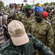 Des militaires marchent dans une foule en liesse.