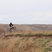 Un garçon saute par-dessus une colline en moto tout terrain à l'automne au Manitoba. 