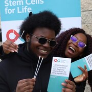 Deux étudiants tiennent des tiges de coton et un document d'enregistrement aux dons de cellules souches.