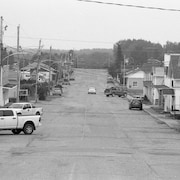 Photo en noir et blanc d'une rue bordée de maisons.