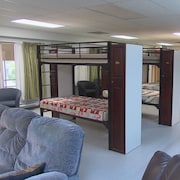 Un dortoir avec  des lits superposés et des canapés à l'avant-plan.