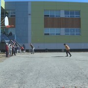 Les jeunes jouent au baseball dans la cour d'école à Kuujjuaq. 