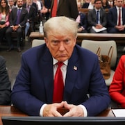 Donald Trump est assis dans la salle d'audience entre deux avocats.