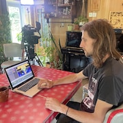 Oli Laroche montre son clip sur un ordinateur. Il est assis dans son appartement.