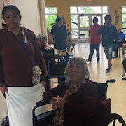 Plusieurs personnes en fauteuil roulant dans une salle commune.