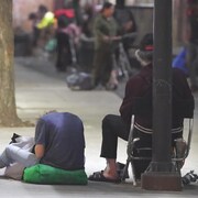 Deux hommes assis sur un trottoir.