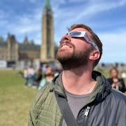 Un homme observe l'éclipse solaire depuis la colline du Parlement, à Ottawa, le 8 avril 2024. 