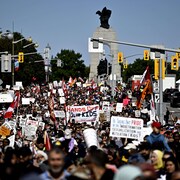 Une foule de manifestants, dont plusieurs brandissant des pancartes, dans une rue d'Ottawa.