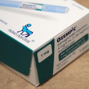 Le coin d'une boîte d'injecteurs Ozempic, avec l'objectif sur le logo de l'entreprise pharmaceutique Novo Nordisk, qui est un dessin de taureau bleu.