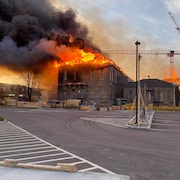 Toute la toiture d'un bâtiment en rénovation est en flammes.