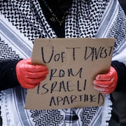 Une manifestante qui porte un keffieh presse l'Université de Toronto de rompre ses liens avec des entreprises israéliennes, lors d'une manifestation à l'Université de Toronto le 20 mars 2024.