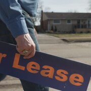 Un homme transporte une pancarte à louer.