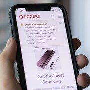 Une personne regarde le message au sujet de la panne de service sur son téléphone portable.
