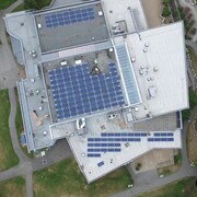 Vue aérienne du toit d'un bâtiment sur lequel sont installés plus d'une centaine de panneaux solaires. 