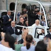 Cyprien Lacroix et le pape François ensemble dans la papemobile. Le véhicule est entouré d'une foule.