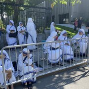 Des sœurs attendent le long de la clôture installée sur la Grande Allée.