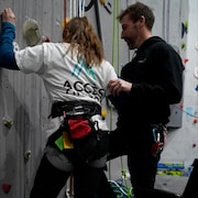 Une jeune fille escalade une paroi.