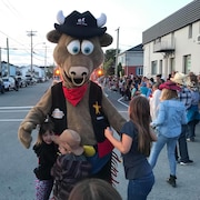 Trois enfants font une accolade à une mascotte de taureau.